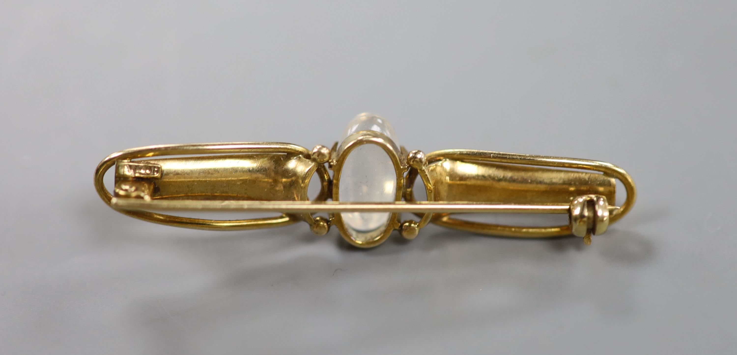 An early 20th century Arts & Crafts 9ct and cabochon moonstone set bar brooch, 47mm, gross weight 3.7 grams.